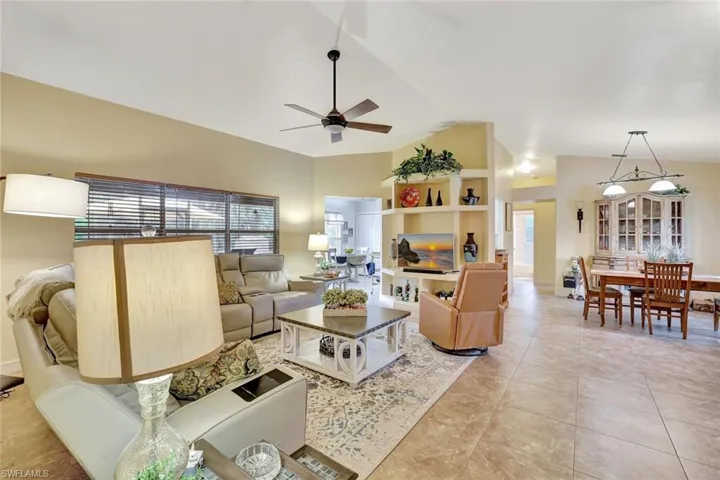Living room featuring ceiling fan, light tile patterned flooring, and high vaulted ceiling