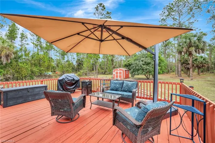 Deck featuring outdoor lounge area, a storage shed, area for grilling, and a yard