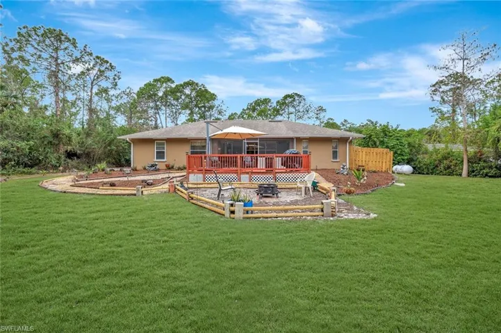 Back of property with a lawn, a wooden deck, a garden, and stucco siding