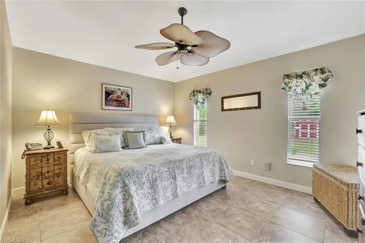 Tiled bedroom featuring a ceiling fan and baseboards