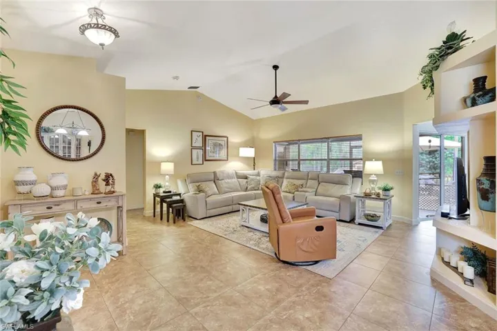 Living area with vaulted ceiling, a ceiling fan, and light tile patterned flooring