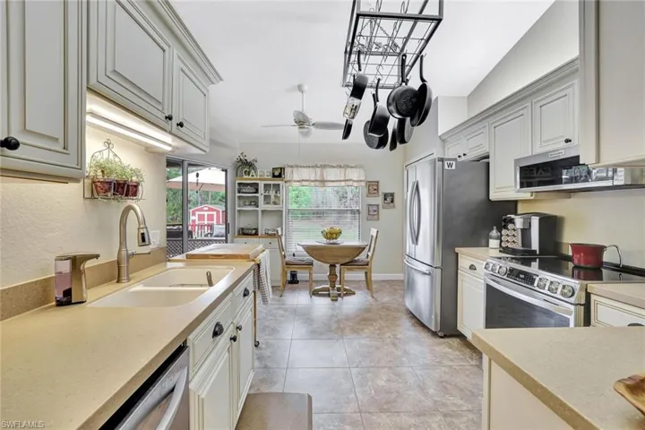 Kitchen featuring stainless steel appliances, ceiling fan, light stone counters, extractor fan, and white cabinets