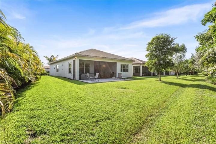 Back of house featuring a lawn, stucco siding, a patio, and a sunroom