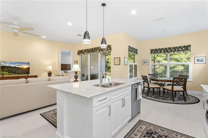 Kitchen featuring light stone counters, white cabinetry, pendant lighting, open floor plan, and recessed lighting