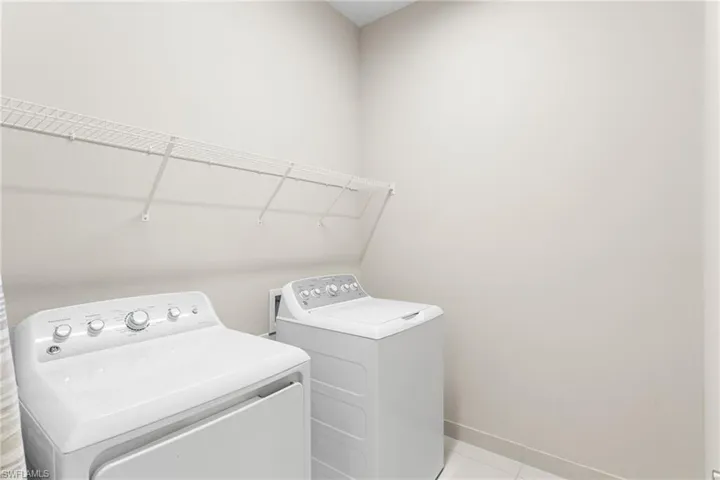 Laundry area with washer and clothes dryer and tile patterned flooring