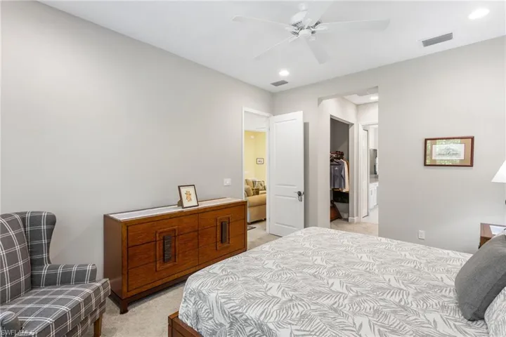 Bedroom featuring a spacious closet, light colored carpet, and a ceiling fan