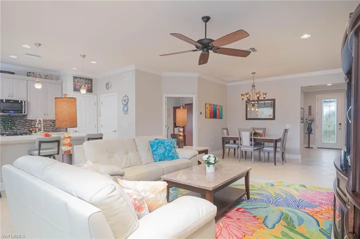 Tiled living room with ceiling fan with and crown molding