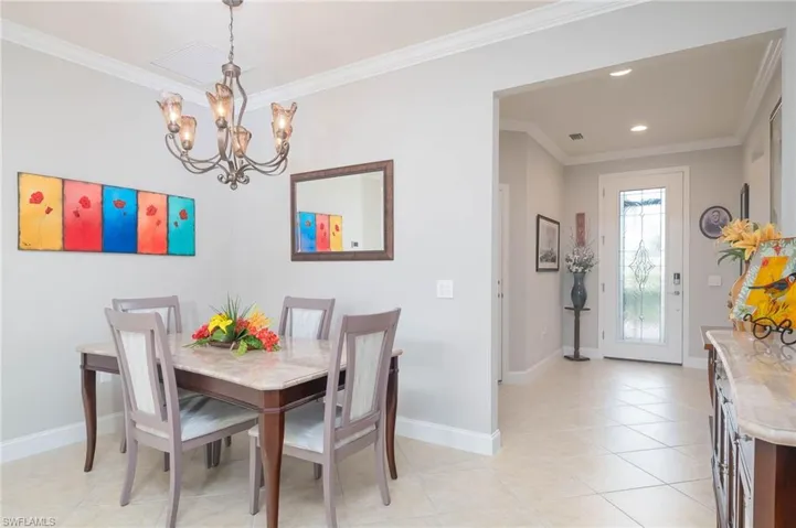 Tiled dining area featuring ornamental molding and a notable chandelier