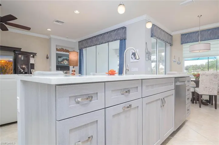 Kitchen with crown molding, white cabinets, decorative light fixtures, and ceiling fan