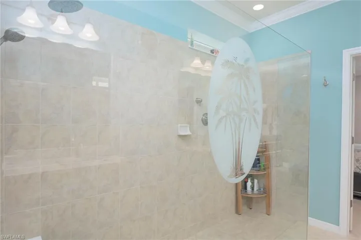 Bathroom featuring tile patterned floors, ornamental molding, and tiled shower