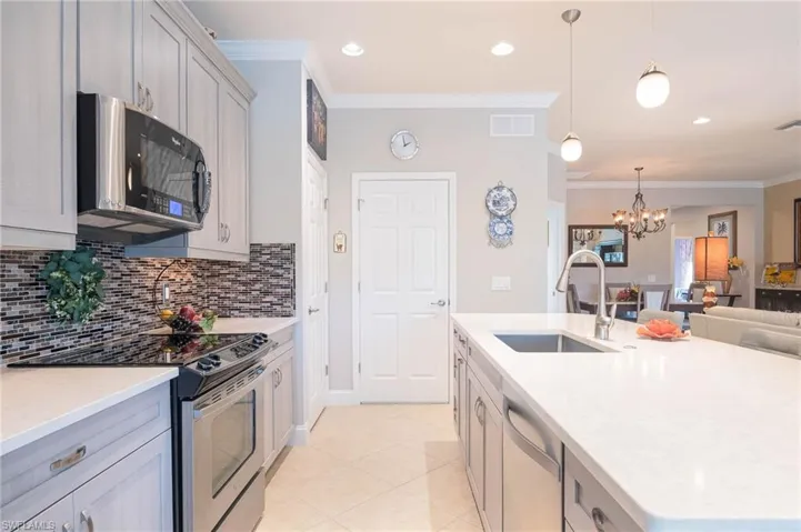 Kitchen with gray cabinetry, an inviting chandelier, sink, appliances with stainless steel finishes, and decorative light fixtures