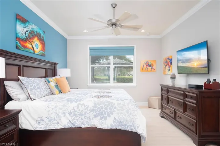 Bedroom with ceiling fan, light hardwood / wood-style floors, and ornamental molding