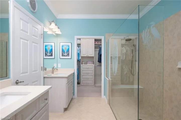 Bathroom featuring vanity, tile patterned floors, an enclosed shower, and crown molding