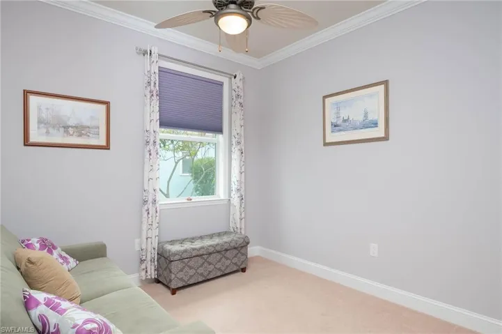 Sitting room with ceiling fan, ornamental molding, and light carpet