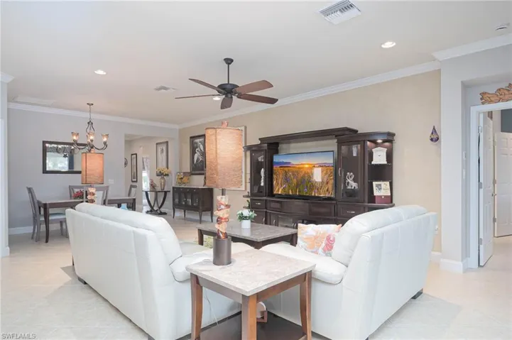 Tiled living room with ceiling fan with and crown molding