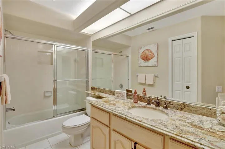 Full bathroom featuring enclosed tub / shower combo, tile patterned floors, vanity, and toilet