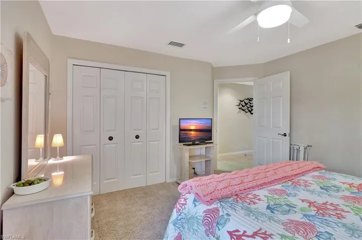 Carpeted bedroom featuring ceiling fan and a closet