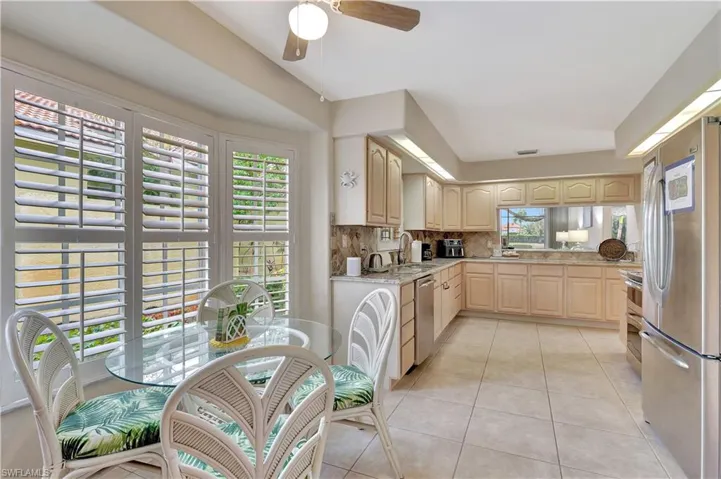 Kitchen featuring appliances with stainless steel finishes, tasteful backsplash, light tile patterned flooring, light brown cabinetry, and sink