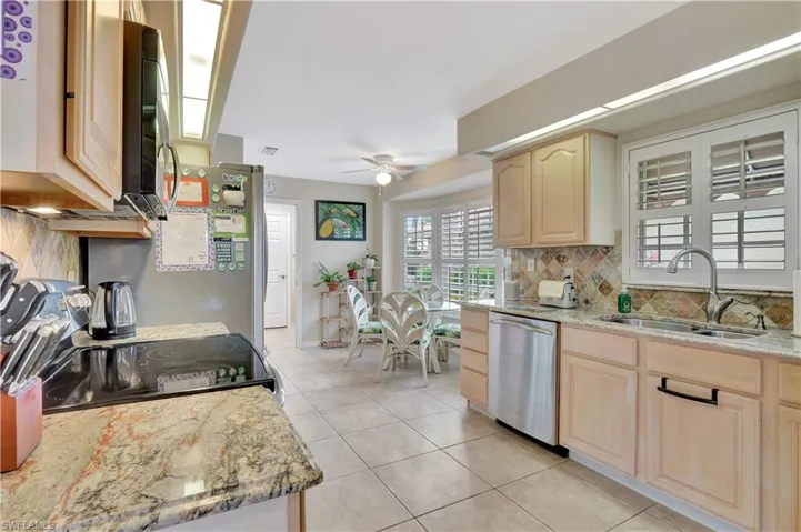 Kitchen featuring light stone countertops, stainless steel appliances, light brown cabinetry, sink, and light tile patterned floors