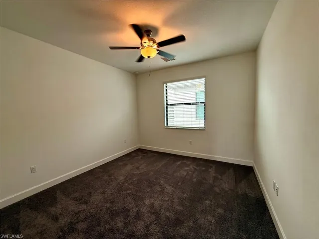 Room featuring neutral wall tones, dark carpeting, and white baseboards