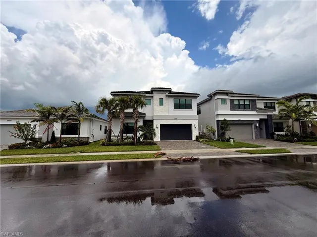 Contemporary two-story residence featuring a white and gray exterior, prominent palm trees, and a two-car garage