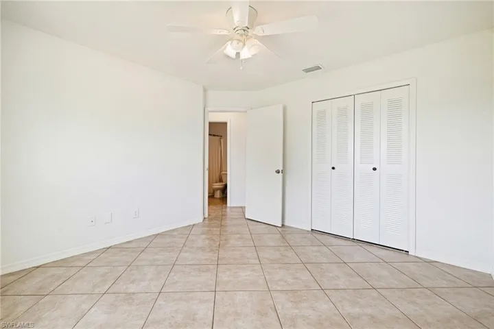 Unfurnished bedroom with ceiling fan, a closet, and light tile patterned floors
