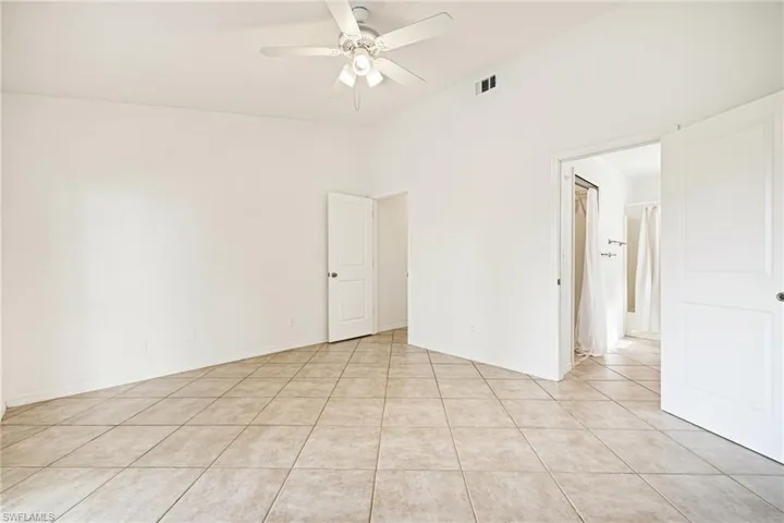 Empty room featuring a ceiling fan, light tile patterned flooring, and vaulted ceiling