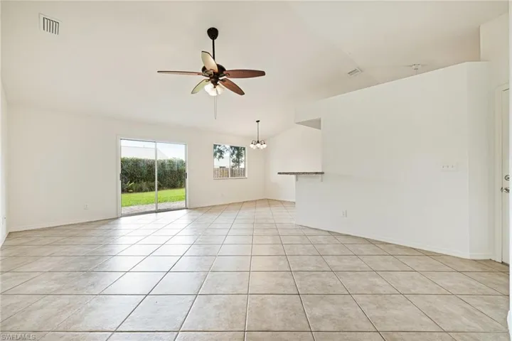 Unfurnished room featuring lofted ceiling, ceiling fan, light tile patterned floors, and a chandelier