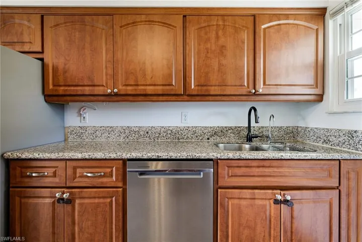 Kitchen featuring stainless steel appliances, light stone counters, and brown cabinets