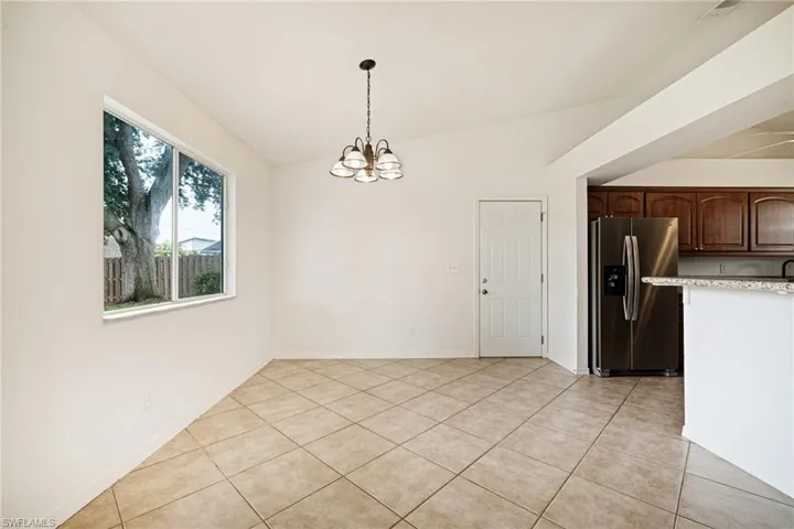 Unfurnished dining area featuring a chandelier, light tile patterned flooring, and vaulted ceiling