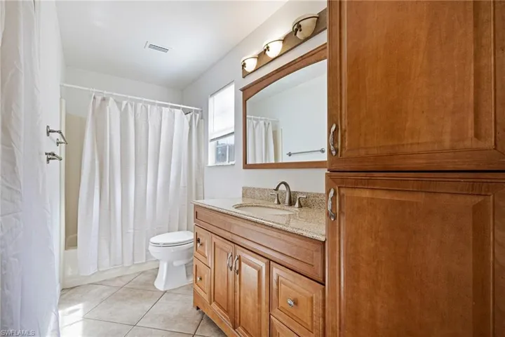 Bathroom featuring vanity, shower / bath combo with shower curtain, and tile patterned floors