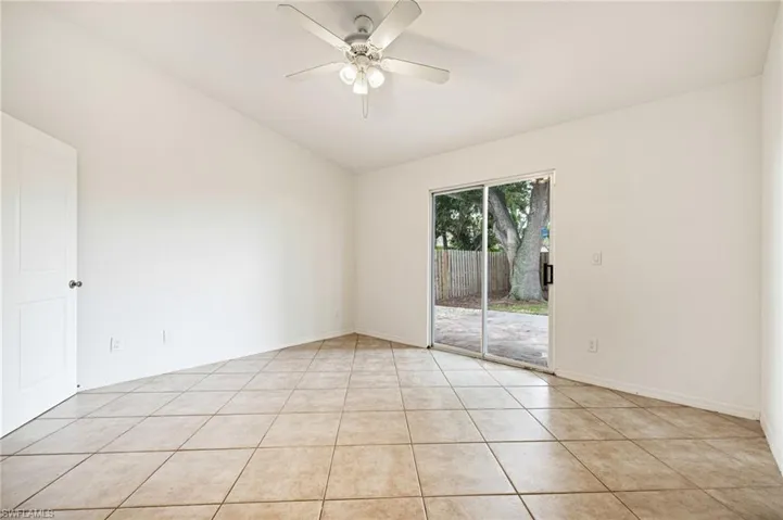 Spare room with vaulted ceiling, ceiling fan, and light tile patterned floors