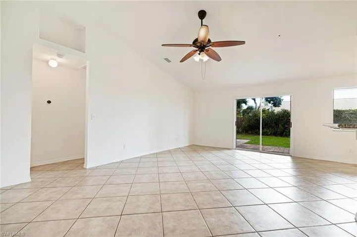 Empty room featuring a ceiling fan, light tile patterned flooring, and high vaulted ceiling