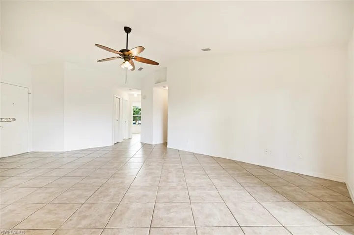 Unfurnished room with light tile patterned flooring, ceiling fan, and vaulted ceiling