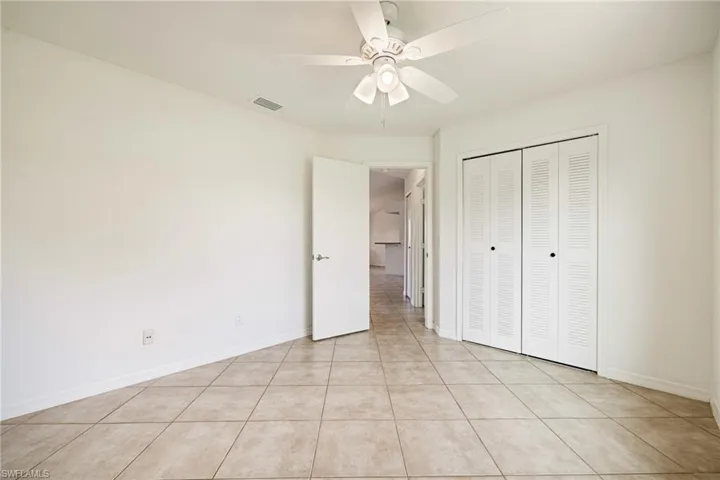 Unfurnished bedroom with a closet, light tile patterned floors, and ceiling fan