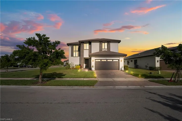 View of front of property featuring a lawn, stucco siding, decorative driveway, and an attached garage
