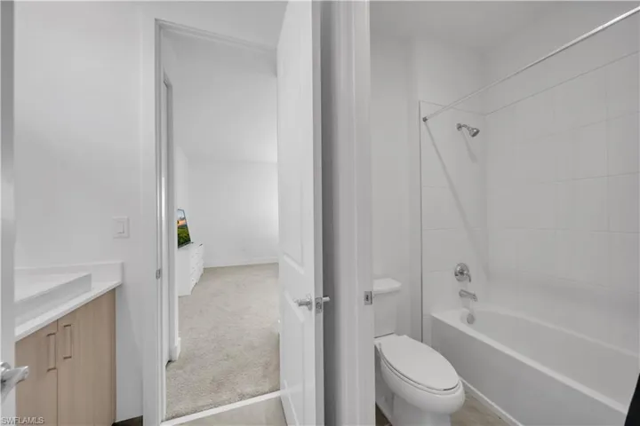 Full bath featuring vanity, washtub / shower combination, and light carpet