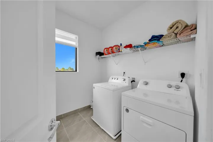 Laundry area with washer and dryer and light tile patterned floors