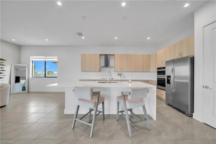 Kitchen featuring light brown cabinets, modern cabinets, stainless steel appliances, a breakfast bar, and an island with sink