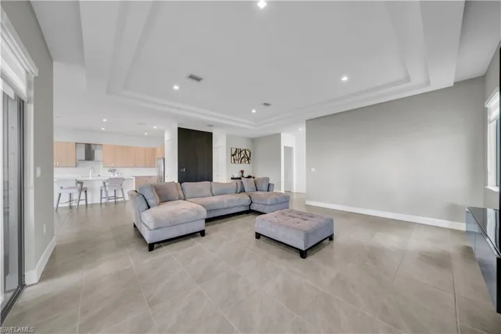 Living room featuring a raised ceiling, recessed lighting, and light tile patterned floors