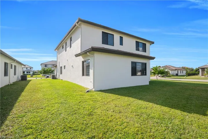 Rear view of property with a yard, stucco siding, and a residential view