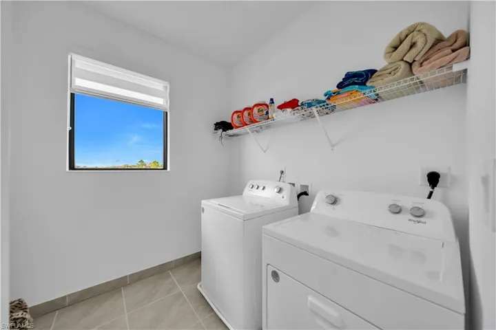 Laundry area with independent washer and dryer and light tile patterned floors