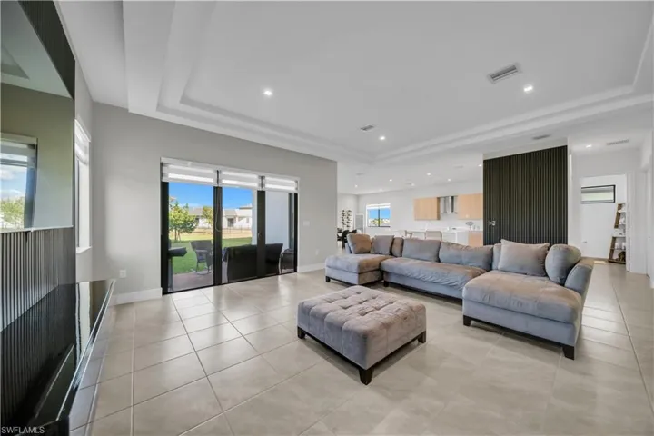 Living area with a raised ceiling, recessed lighting, and light tile patterned flooring