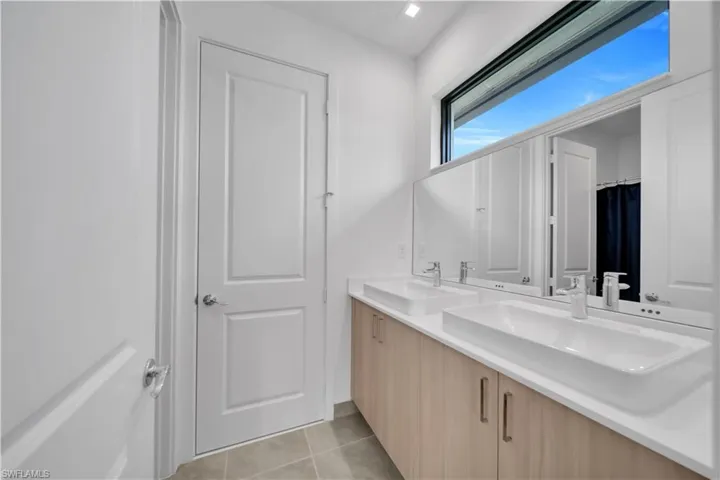 Bathroom with double vanity, a shower with curtain, and light tile patterned floors