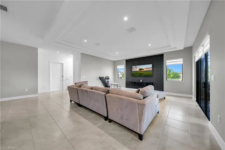 Living room featuring a tray ceiling, light tile patterned floors, and recessed lighting