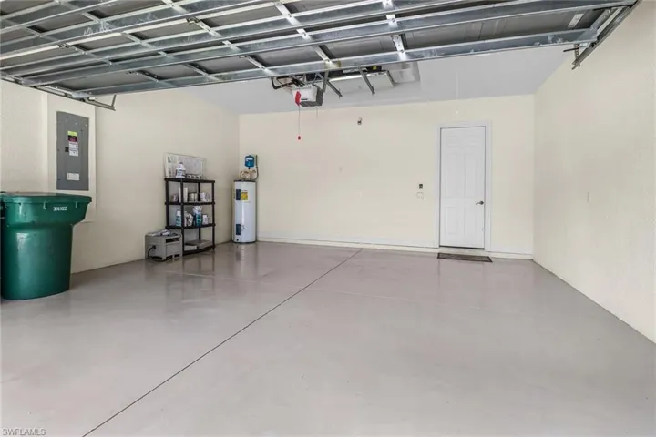 Garage featuring a garage door opener and electric water heater