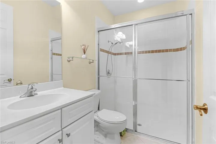 Bathroom featuring tile floors, walk in shower, toilet, and vanity