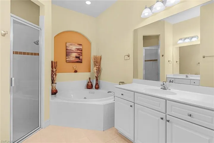 Bathroom with dual bowl vanity, tile flooring, and separate shower and tub