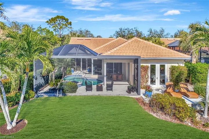 Back of property featuring glass enclosure, a patio area, a yard, and french doors