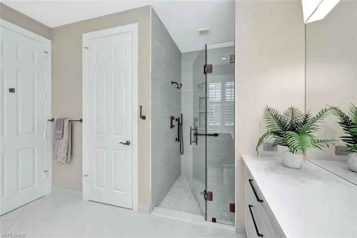 Bathroom featuring tile patterned floors, a shower with door, and vanity